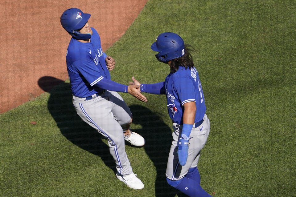 Toronto Blue Jays' Bo Bichette, right, and Daulton Varsho celebrate after scoring during the first inning of an opening day baseball game against the St. Louis Cardinals Thursday, March 30, 2023, in St. Louis. (AP Photo/Jeff Roberson)