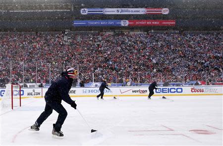 An ice crew shovels snow off the ice during a stoppage in play in the second period during the 2014 Winter Classic hockey game between the Detroit Red Wings and the Toronto Maple Leafs at Michigan Stadium. Mandatory Credit: Rick Osentoski-USA TODAY Sports