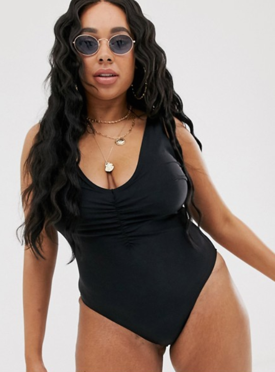 A photo of a model wearing ASOS DESIGN curve deep plunge minimal swimsuit in black.