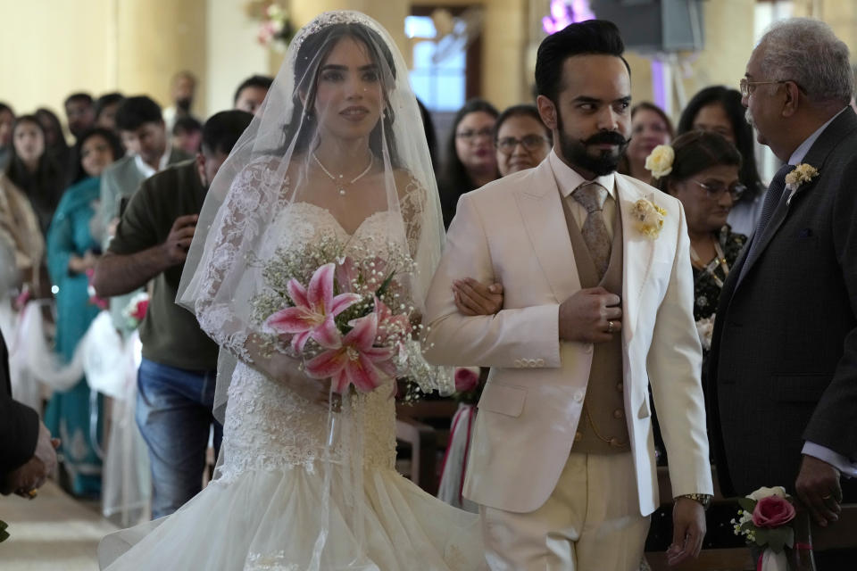 Pakistani Christian groom Sharoon Arjumand John arrives with his bride Yamima Teresa Bhagtaney for their wedding ceremony at Holy Trinity Cathedral in Karachi, Pakistan, Saturday, Jan. 27, 2024. Pakistan's winter months are all about weddings. The cooler temperatures between November and February see millions of people attending festivities every week. The wedding season has become a calendar fixture, like birthdays. It even has a nickname, Decemberistan. (AP Photo/Fareed Khan)