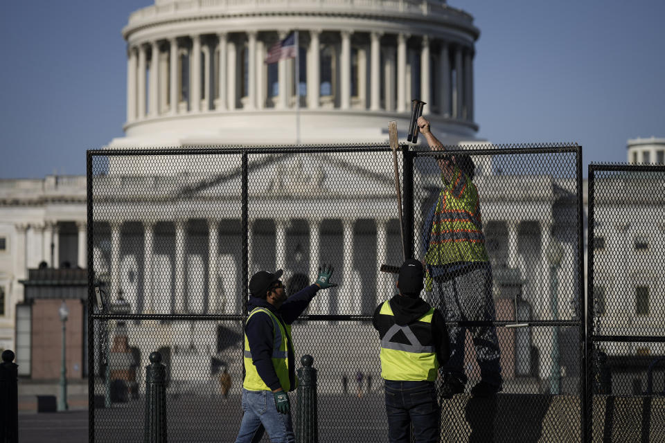 Three workers install security fencing around the U.S. Capitol.