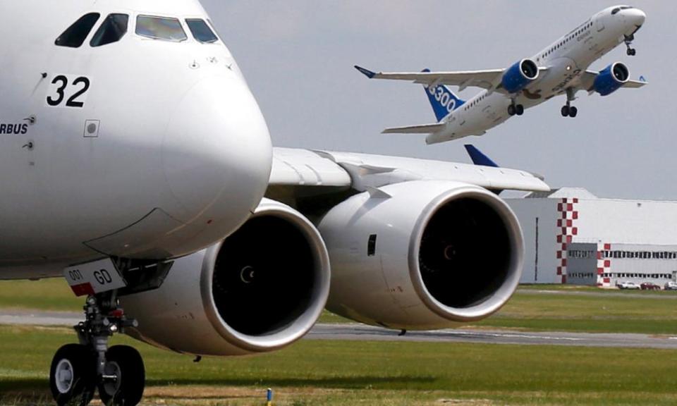 A Bombardier CS300 aicraft takes off as an Airbus A380 waits on the taxiway during an air show. 