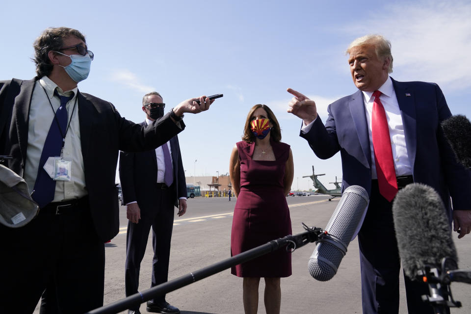 President Donald Trump talks to reporters at Phoenix Sky Harbor International Airport, Monday, Oct. 19, 2020, in Phoenix. Second from right is Sen. Martha McSally, R-Ariz. (AP Photo/Alex Brandon)