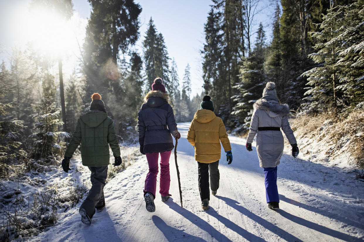  Four women walk down a snow covered road. 