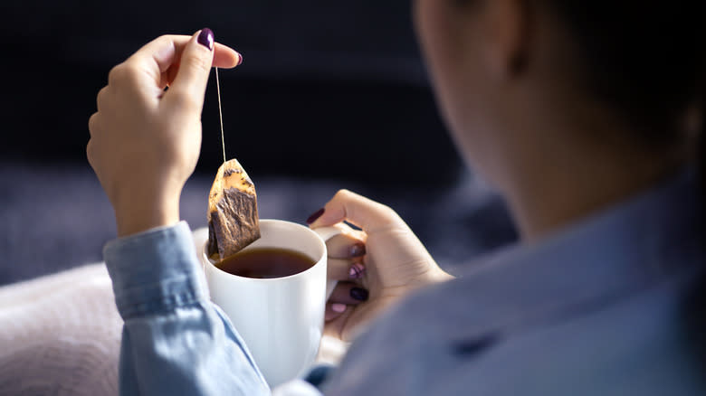 A person steeping a tea bag in a cup of tea