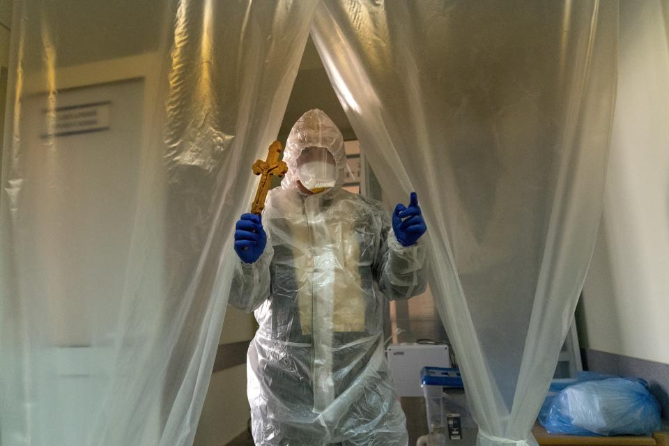 Father Stephan, Ukrainian Greek Catholic Church priest, wearing a special suit to protect himself against coronavirus enters an intensive care unit of the emergency hospital to visit visiting patients with COVID-19 in Lviv, Western Ukraine, Saturday, Jan. 9, 2021. (AP Photo/Evgeniy Maloletka)