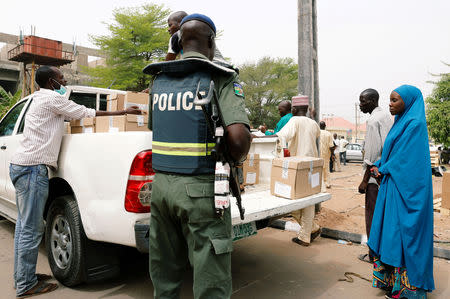 A police member oversees Ad-hoc staff loading boxes onto a truck during the distribution of election materials at the INEC office in Yola, in Adamawa State, Nigeria February 15, 2019. REUTERS/Nyancho NwaNri