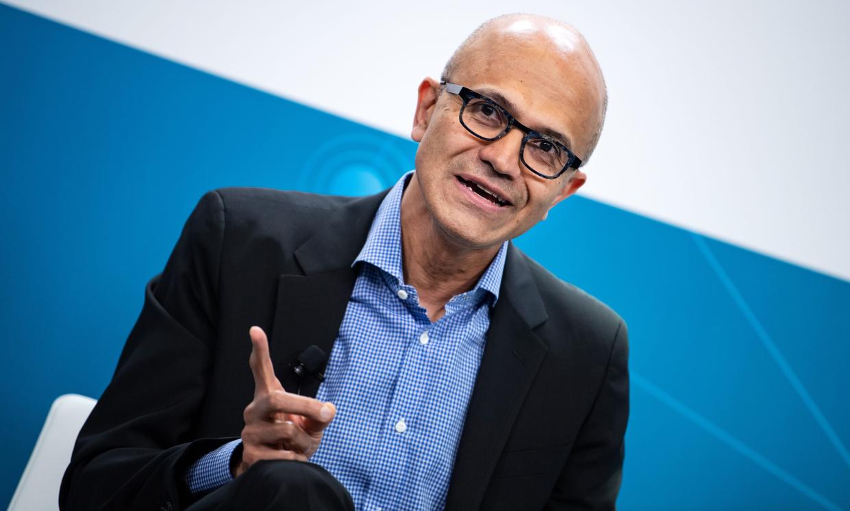 Microsoft CEO Satya Nadella points with one finger on stage.
