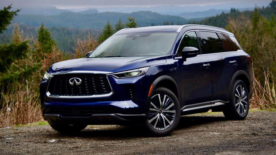 2023 Infiniti QX60 Sensory AWD in dark blue. The SUV is against a forested, mountainous background