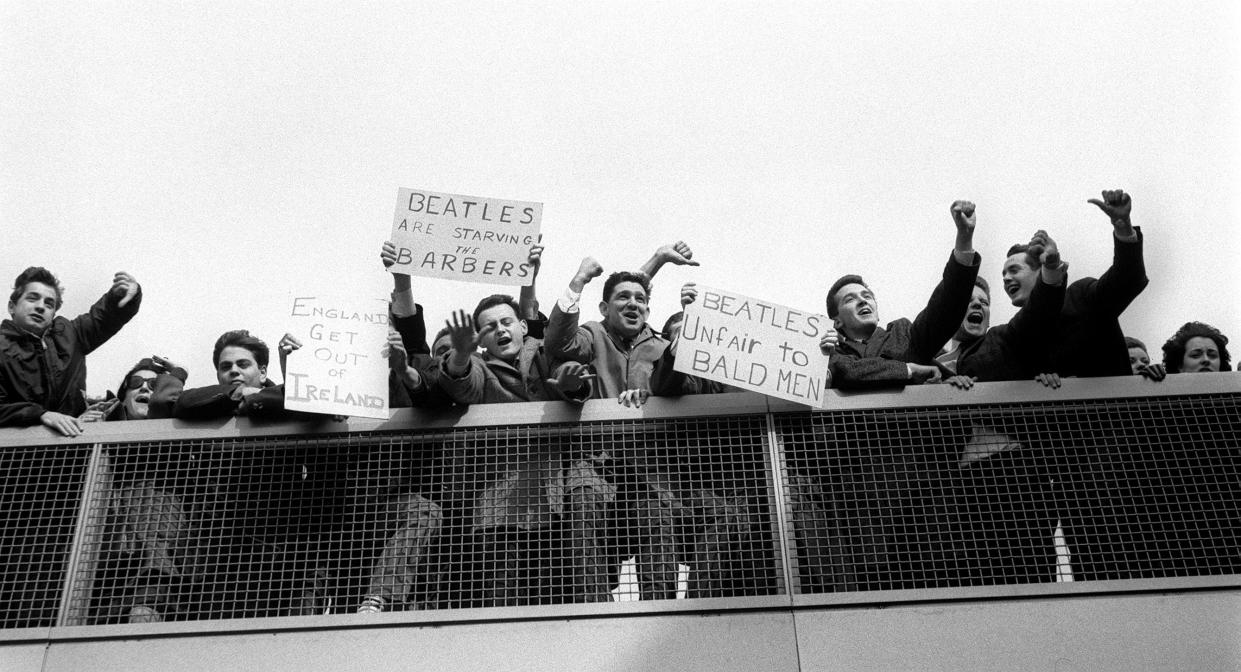 Protesters and enthusiastic banners greet the Beatles 