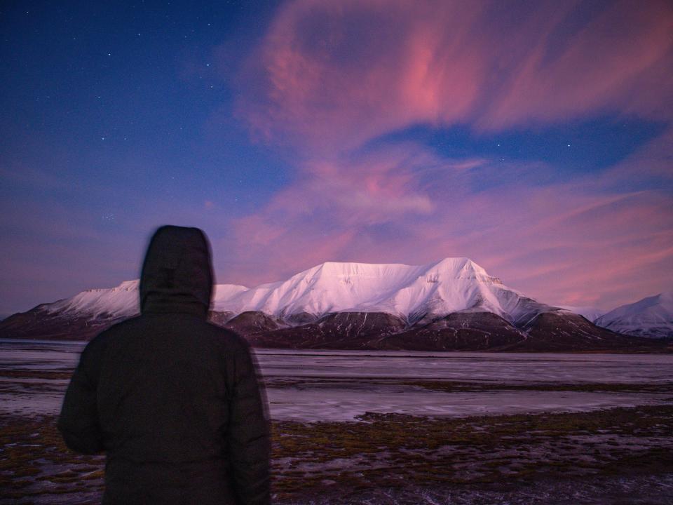 The writer stands in front of a pink sky