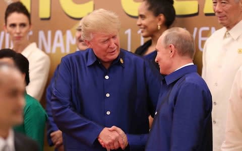 Donald Trump shakes hands with Russia's President Vladimir Putin as they pose for a group photo ahead of the Asia-Pacific Economic Cooperation (APEC) Summit leaders gala dinner in the central Vietnamese city of Danang on November 10 - Credit: AFP