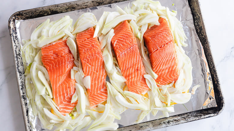 raw salmon and sliced fennel on baking sheet
