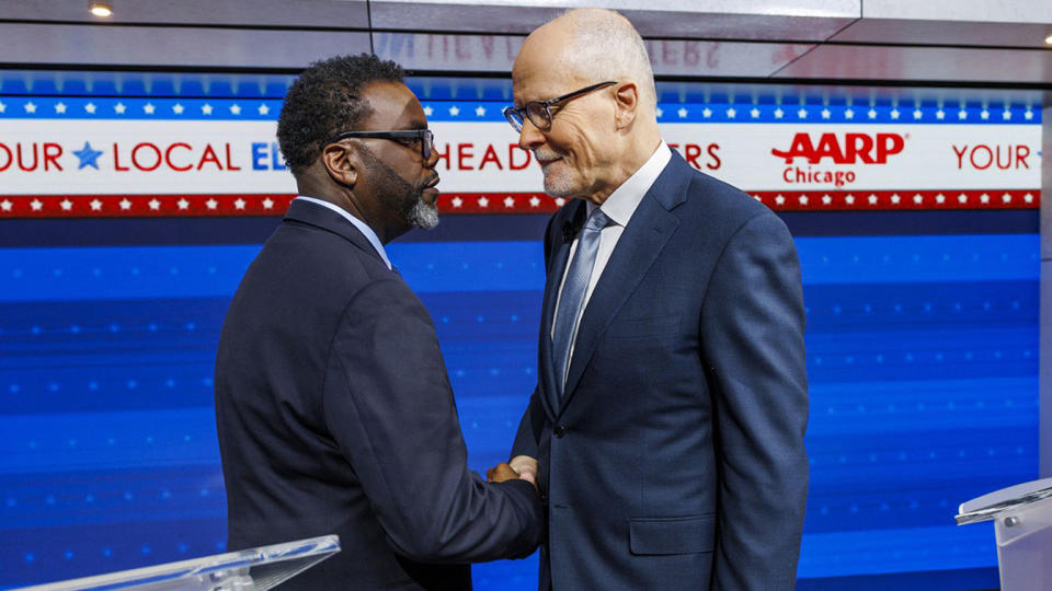 Chicago mayoral candidates Brandon Johnson and Paul Vallas shake hands on a debate stage.