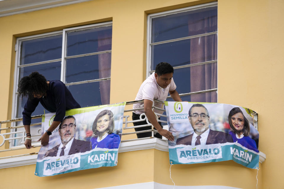Members of Seed Movement party place a banners with photos of their presidential candidate Bernardo Arevalo and running mate Karin Herrera at his office in Guatemala City, Thursday, July 13, 2023. On Wednesday, the Attorney General's Office announced that a judge had suspended the legal status of the Seed Movement party, for alleged violations when it gathered the necessary signatures to form. Arévalo and Herrera had been set to compete in a runoff election on Aug. 20. (AP Photo/Moises Castillo