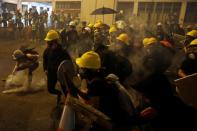 An anti-extradition bill demonstrator picks up a tear gas canister during clashes with riot police after a march to call for democratic reforms, in Hong Kong