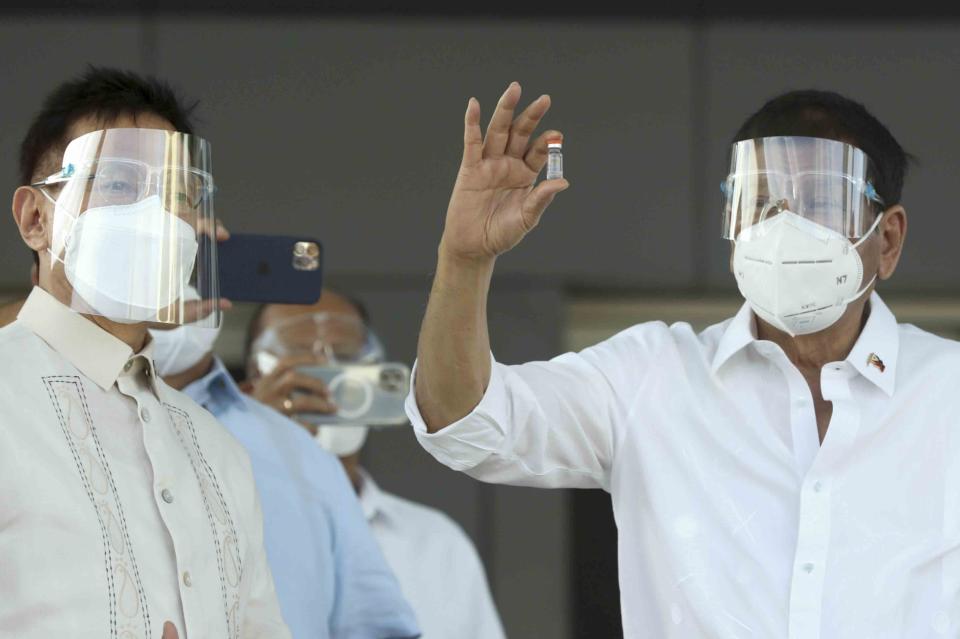 In this photo provided by the Malacanang Presidential Photographers Division, Philippine President Rodrigo Duterte, right, holds a vial containing the Sinovac vaccine from China as it arrives at the Villamor Air Base in Manila, Philippines on Sunday Feb. 28, 2021. The Philippines received its first batch of COVID-19 vaccine Sunday, among the last in Southeast Asia to secure the critical doses despite having the second-highest number of coronavirus infections and deaths in the hard-hit region. (Toto Lozano/Malacanang Presidential Photographers Division via AP)