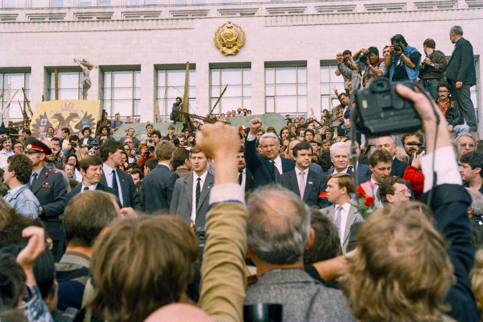 A crowd of people with some raising their fists.