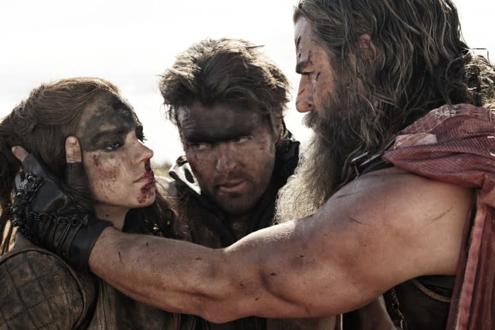 Tom Burke stands between Anya Taylor-Joy and Chris Hemsworth in Furiosa: A Mad Max Saga.