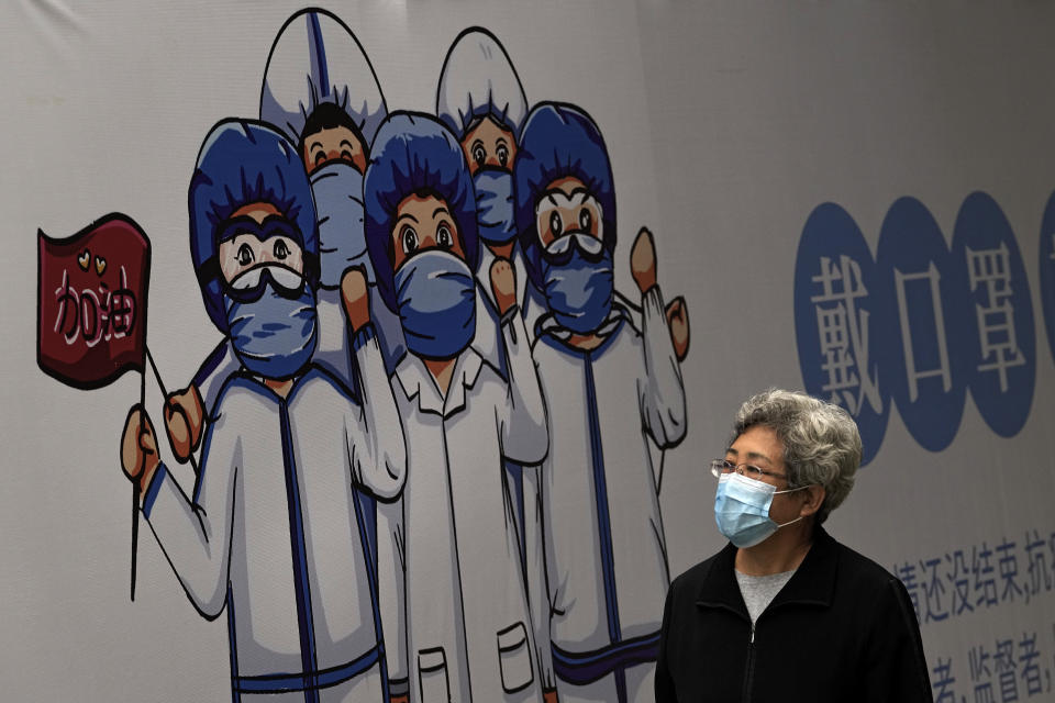 A woman wearing a face mask to help curb the spread of the coronavirus walks by a billboard depicting medical workers flight against the COVID-19 bearing the words "Wear Face Mask" on display along a hutong alley in Beijing, Thursday, Oct. 14, 2021. (AP Photo/Andy Wong)