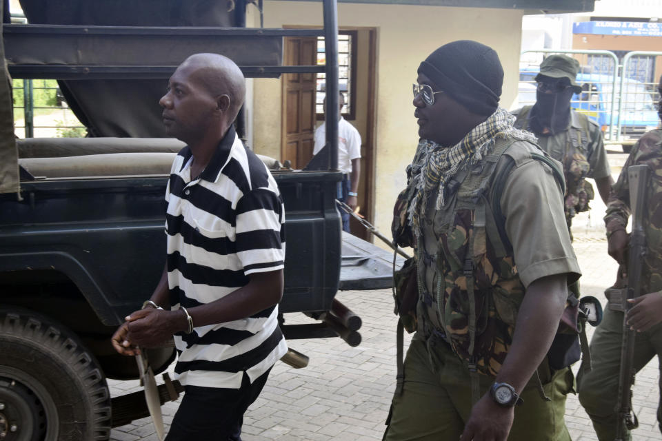 Cult preacher Pastor Paul Nthenge Mackenzie, left, arrives at the Malindi Law Courts under tight security, Friday Dec. 1, 2023 for the sentencing of his 2019 case where he had been charged with three counts of being in possession of films intended to incite children against attending school and incite Christians, Hindus, Buddhists and Islams on their religion. In the second count, he was found guilty of being on procession and distributing films to the public which had not been examined and classified by Kenya Films Classifications Board. The third charge stated that he was found operating a films studio and producing films for public consumption without first registering as a film agent and acquiring a filming license. He was jailed for eighteen months imprisonment for the three counts. (AP Photo/Gideon Maundu).