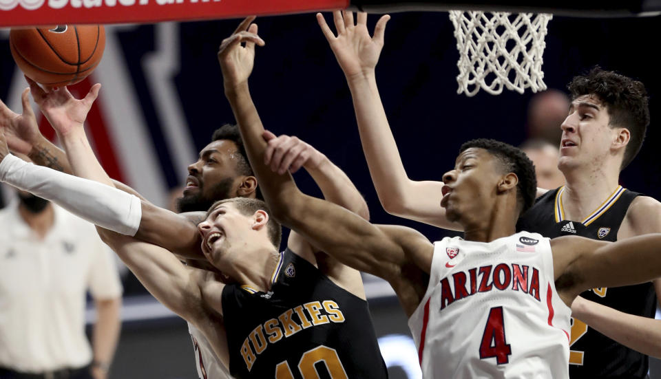 Arizona forward Jordan Brown (21), left, and guard Dalen Terry (4) tangle with Washington guard Erik Stevenson (10) and center Riley Sorn (52) for control of a rebound in the first half of an NCAA college basketball game Saturday, Feb. 27, 2021, in Tucson, Ariz. (Kelly Presnell/Arizona Daily Star via AP)