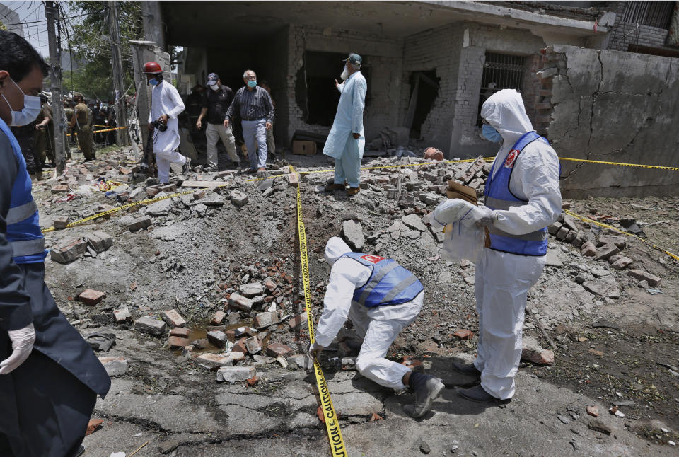 Investigators collect evidence at the site of explosion in Lahore, Pakistan, Wednesday, June 23, 2021. A powerful explosion ripped through a residential area in the eastern city of Lahore on Wednesday, killing few people and injuring some others, police and rescue officials said. (AP Photo/K.M. Chaudary)