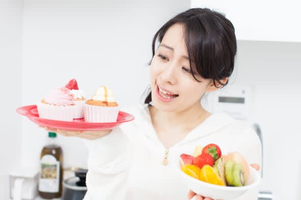 Smiling young woman holding cupcake and fruits