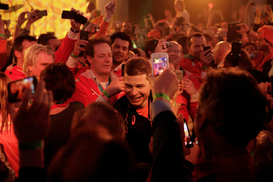 Under orange lighting, gold medallist Sven Kramer of the Netherlands walks through a crowd of cheering fans after winning the gold in the men's 5,000-meter speedskating race at the 2014 Winter Olympics in Sochi, Russia, Saturday, Feb. 8, 2014. Kramer set a new Olympic record in the race. (AP Photo/Matt Dunham)