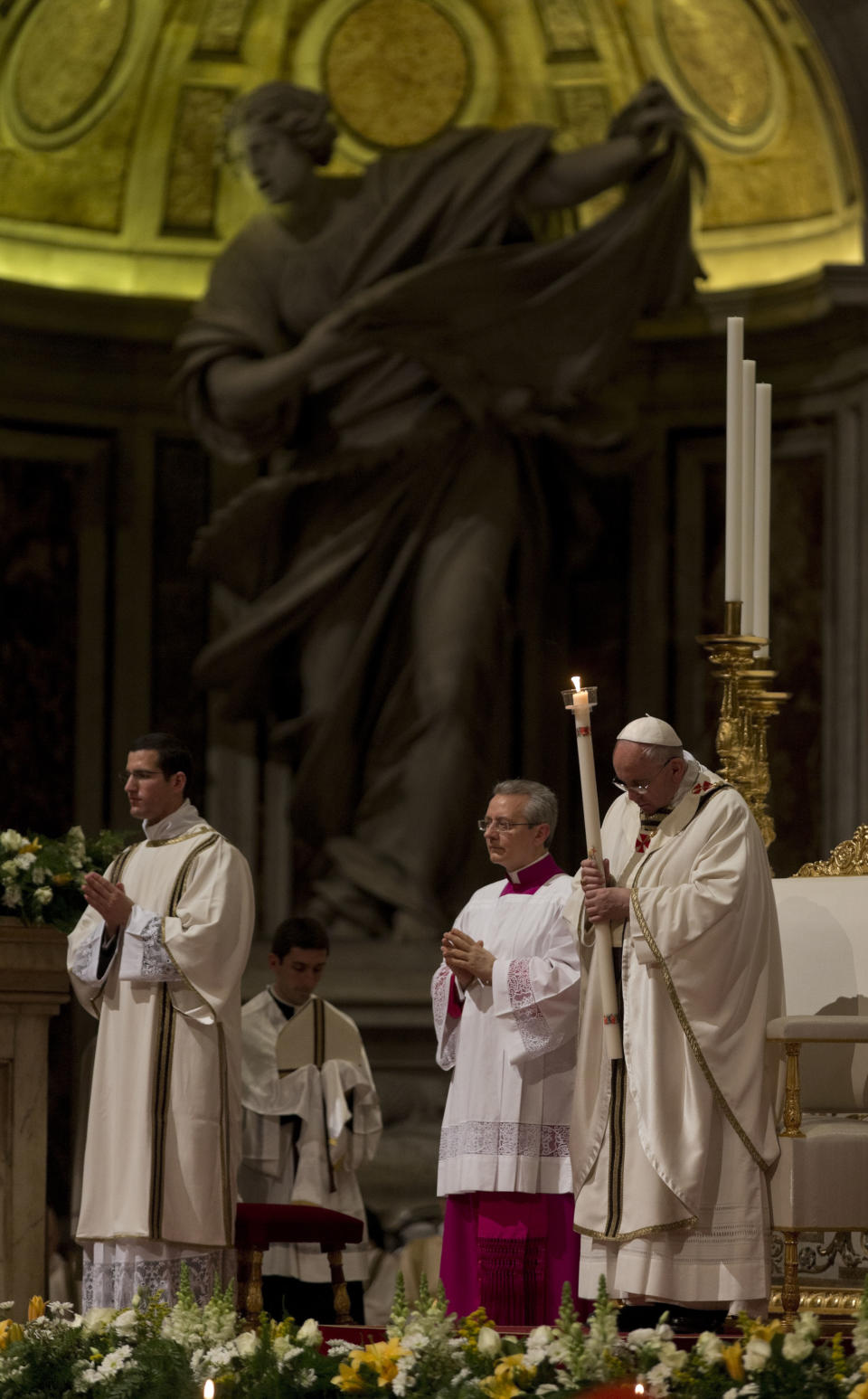 Pope Francis holding a tall, lit, white candle, enters St. Peter's Basilica to begin the Easter vigil service, at the Vatican, Saturday, April 19, 2014. (AP Photo/Alessandra Tarantino)