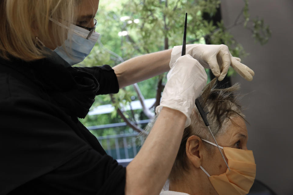 A woman gets a hair cut at a hairdressing salon in Sevres, outside Paris, Monday, May 11, 2020. The French began leaving their homes and apartments for the first time in two months without permission slips as the country cautiously lifted its lockdown. Clothing stores, coiffures and other businesses large and small were reopening on Monday with strict precautions to keep the coronavirus at bay. (AP Photo/Christophe Ena)