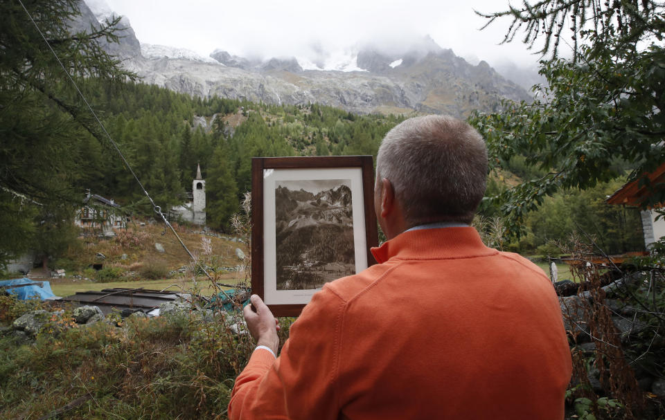 Marco Belfrond holds an old photo the Plancipieux glacier, near Courmayeur, northern Italy, Thursday, Sept. 26, 2019. Italian officials sounded an alarm Wednesday over climate change due to the threat that a fast-moving melting glacier is posing to the picturesque Val Ferret valley near the Alpine town of Courmayeur. The Planpincieux glacier, which spreads 1,327 square kilometers (512 square miles) across the Grande Jorasses peak of the Mont Blanc massif, has been moving up to 50 centimeters (nearly 20 inches) a day (AP Photo/Antonio Calanni)