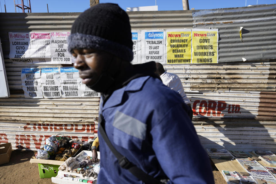 A man walks past newspaper banners, in Harare, Monday, July 25, 2022. Zimbabwe on Monday launched gold coins to be sold to the public to try to tame runaway inflation that has further eroded the country’s unstable currency. (AP Photo/Tsvangirayi Mukwazhi)