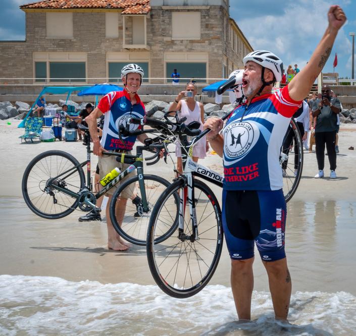 Chuck Keels celebrates completing his cross-country bike ride from San Diego to St. Augustine Beach as he wades into the Atlantic Ocean, off St. Augustine Beach, on Friday, June 10, 2022.