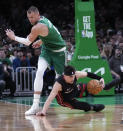 Miami Heat guard Tyler Herro, right, fouls Boston Celtics center Kristaps Porzingis, top, while dropping to the court during the second half of Game 2 of an NBA basketball first-round playoff series, Wednesday, April 24, 2024, in Boston. (AP Photo/Charles Krupa)