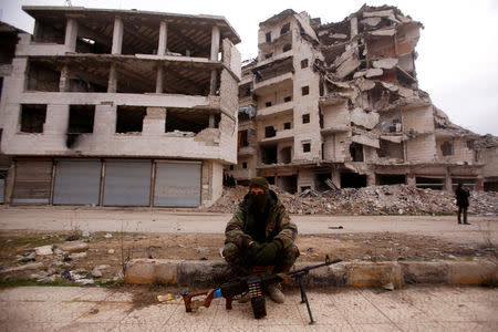 A member of forces loyal to Syria's President Bashar al-Assad sits near damaged buildings in Aleppo's Salaheddine district, Syria December 16, 2016. REUTERS/Omar Sanadiki