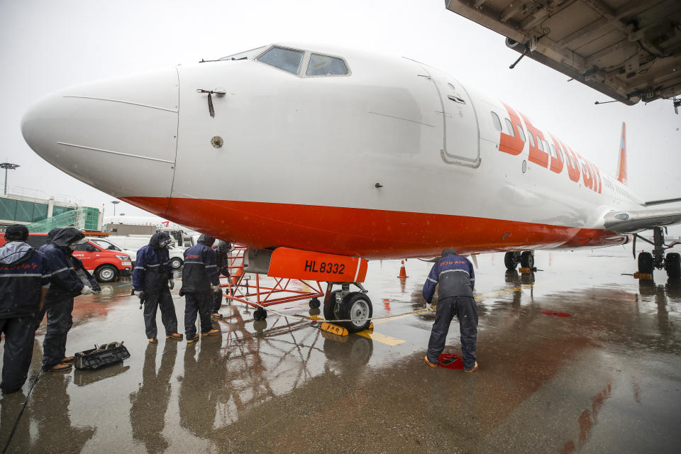 Jeju Air's mechanics tie up a plane on the tarmac as Typhoon Hinnamnor moves toward the Korean Peninsula at Gimpo International Airport in Seoul, South Korea, Monday, Sept. 5, 2022. Hundreds of flights were grounded and more than 200 people evacuated in South Korea on Monday as Typhoon Hinnamnor approached the country's southern region with heavy rains and winds of up to 290 kilometers (180 miles) per hour, the strongest storm in decades. (Korea Pool/Yonhap via AP)