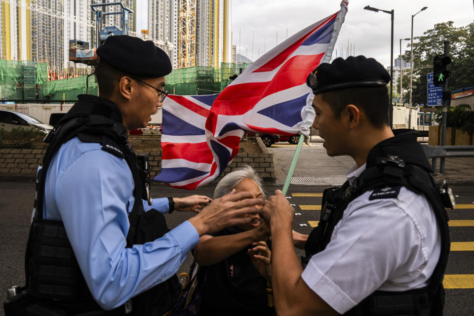 A pro-democracy activist known as "Grandma Wong," center, is escorted by police outside the West Kowloon courts as closing arguments open in Hong Kong's largest national security trial of 47 pro-democracy figures in Hong Kong, Wednesday, Nov. 29, 2023. (AP Photo/Louise Delmotte)