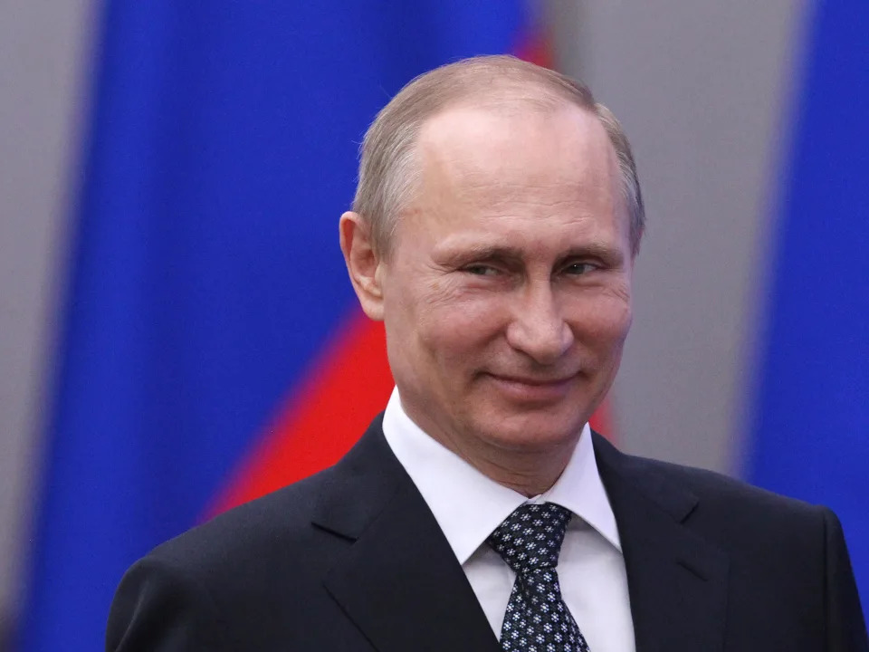 Vladimir Putin smiles.