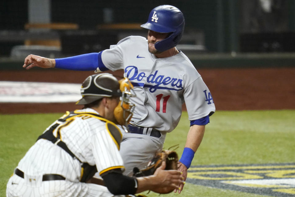 Los Angeles Dodgers' A.J. Pollock (11) beats the throw to score on a single by Joc Pederson during the third inning in Game 3 of a baseball National League Division Series Thursday, Oct. 8, 2020, in Arlington, Texas. At left is San Diego Padres catcher Jason Castro.(AP Photo/Sue Ogrocki)