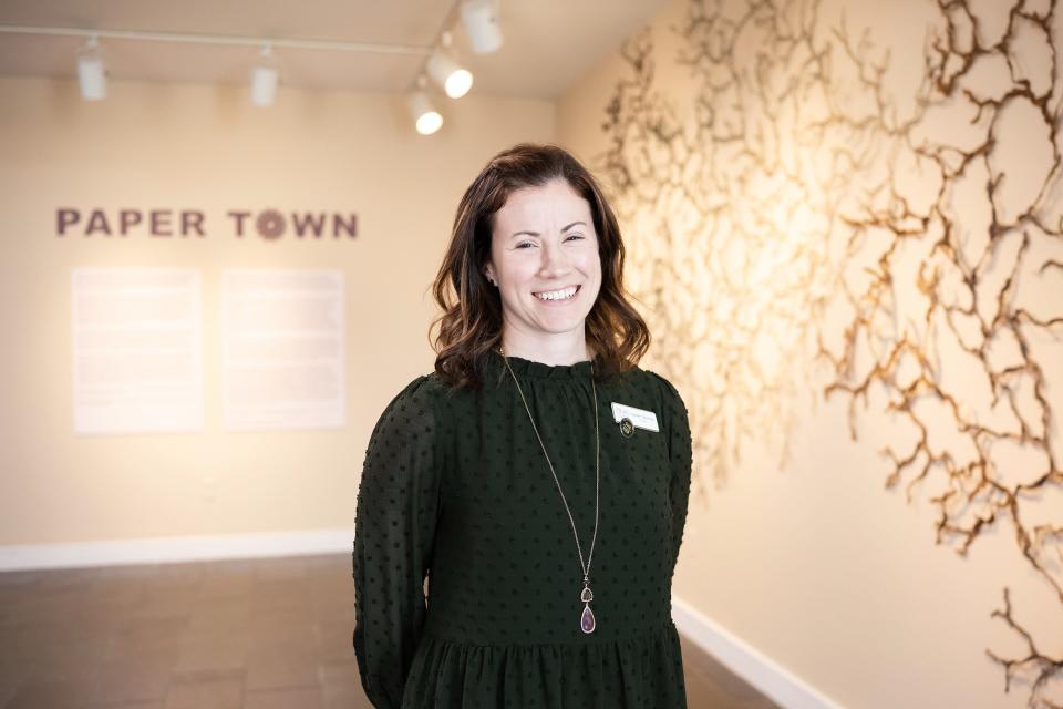 Gallery curator Lauren Szumita poses by the entrance to "Paper Town" at Fitchburg Art Museum on Sunday April 02, 2023.