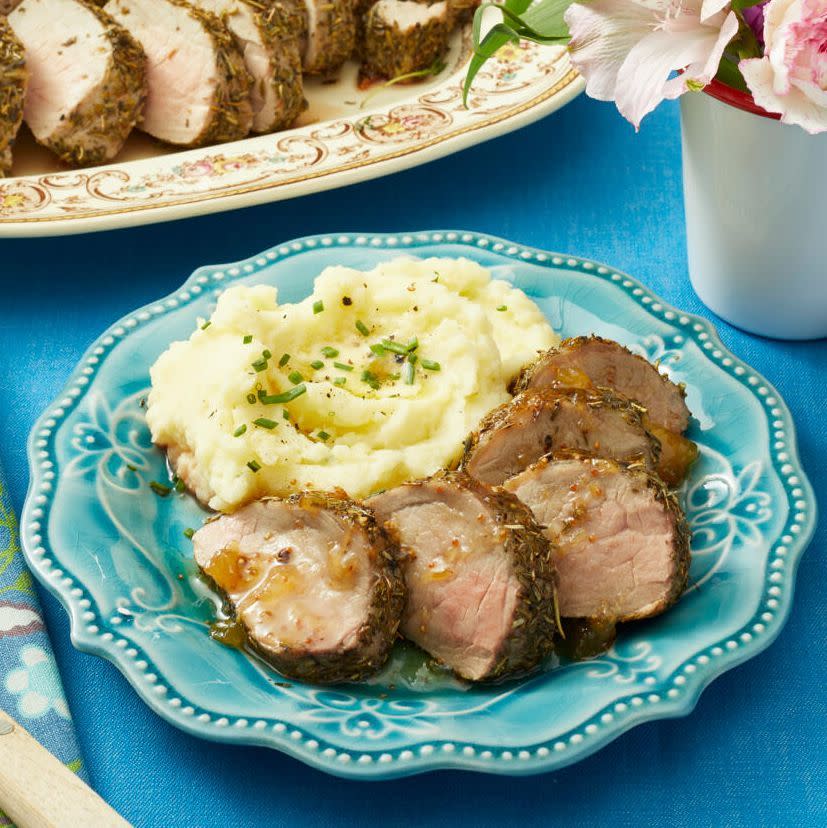 herb roasted pork tenderloin with preserves sliced on blue plate with mashed potatoes