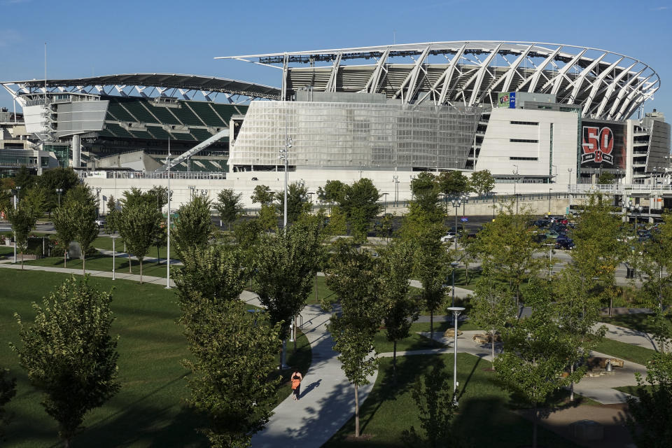 FILE - A pedestrian runs through Smale Park on the Ohio River front near Paul Brown Stadium, home of the Cincinnati Bengals NFL Football team, as a celebratory 50th anniversary banner is displayed outside its gates, Thursday, Sept. 28, 2017, in Cincinnati. There are 23 venues bidding to host soccer matches at the 2026 World Cup in the United States, Mexico and Canada. (AP Photo/John Minchillo, File)