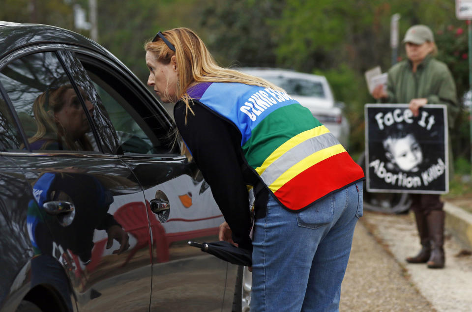 FILE - In this March 20, 2018, file photo, clinic escort Kim Gibson speaks with driver as they attempt to enter the Jackson Women's Health Organization's clinic parking lot, the only facility in the state that performs abortions in Jackson, Miss. Mississippi and Kentucky enacted bills that would ban most abortions after a fetal heartbeat is detected, as early as six weeks into pregnancy. (AP Photo/Rogelio V. Solis, File)