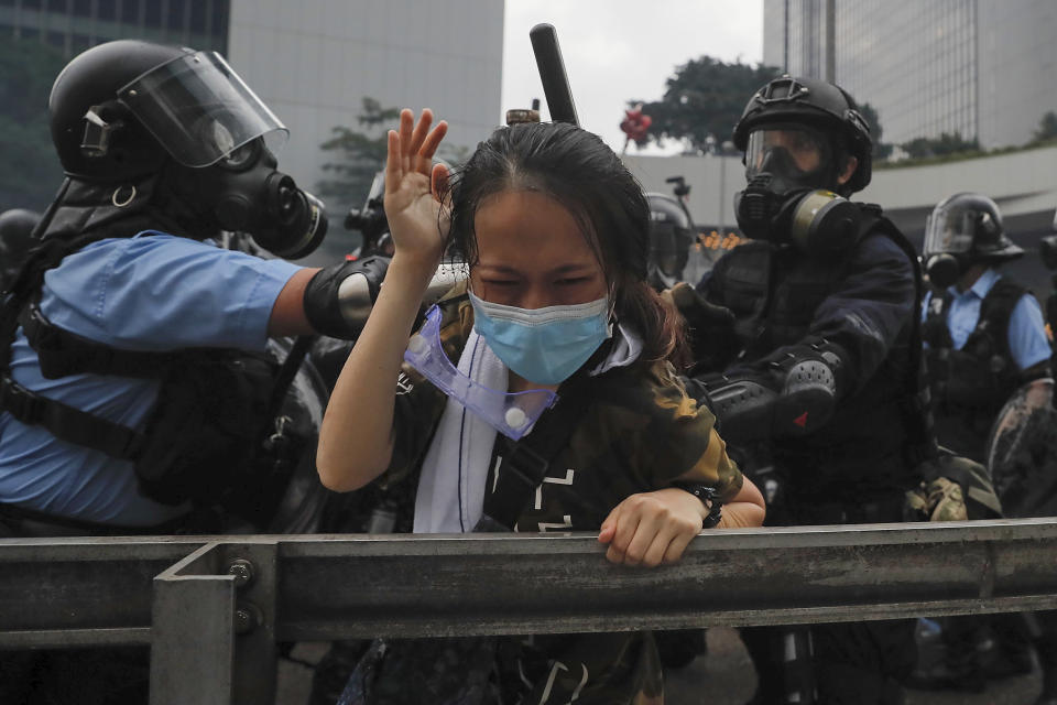 A protester reacts as she tackled by riot police during a massive demonstration outside the Legislative Council in Hong Kong, Wednesday, June 12, 2019. Hong Kong police have used tear gas and high-pressure hoses against thousands of protesters opposing a highly controversial extradition bill outside government headquarters. (AP Photo/Kin Cheung)