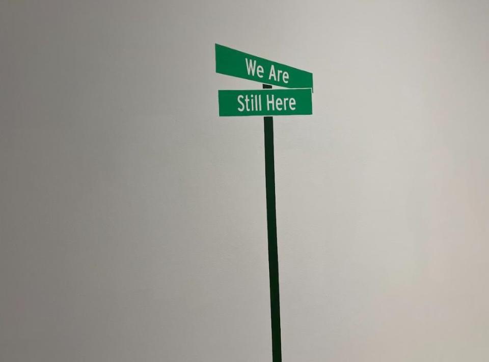 The entrance to the exhibition features a poignant street sign with the words "We Are Still Here." A secondary message is found elsewhere in the museum with the same message in Anishinaabemowin.