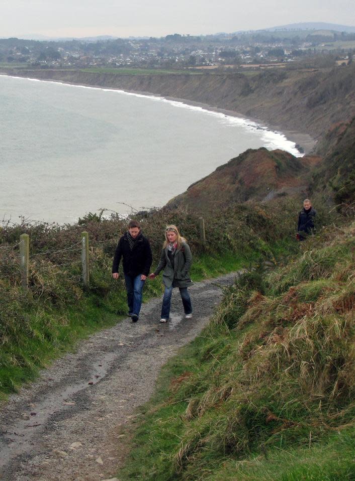 This Feb. 17, 2013 photo shows a couple hiking uphill on the Bray-to-Greystones cliff walk south of Dublin, Ireland. The town of Greystones is in the background. The 8-kilometer (5-mile) path closely parallels Dublin's commuter train line along the coast, and hikers can catch the train back to Dublin from either Bray or Greystones. (AP Photo/Shawn Pogatchnik)