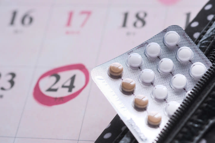 Birth control pills sitting next to a calendar