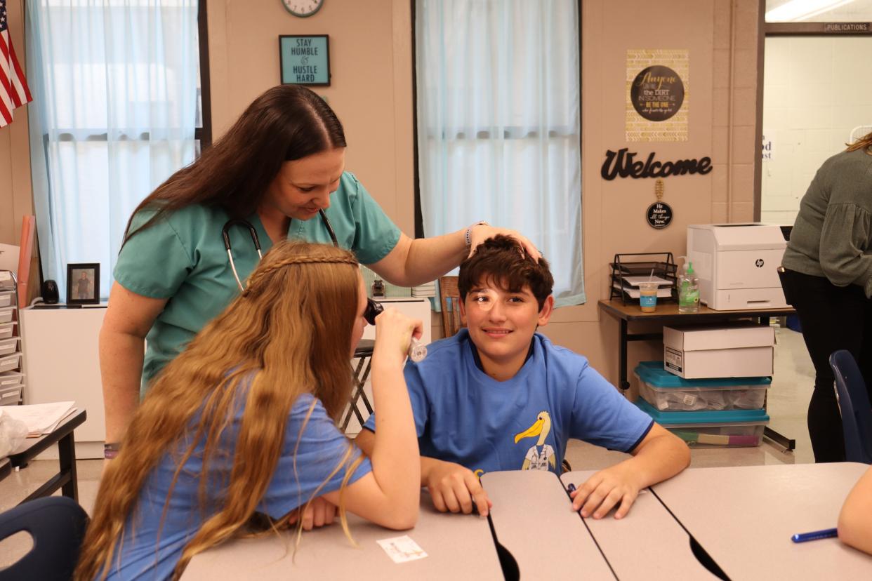 Rhonda Foster holds Gunner Whitt's head as Tori Brouillette looks into his eye on Oct. 11 during a MedStart presentation at Poland Junior High School.