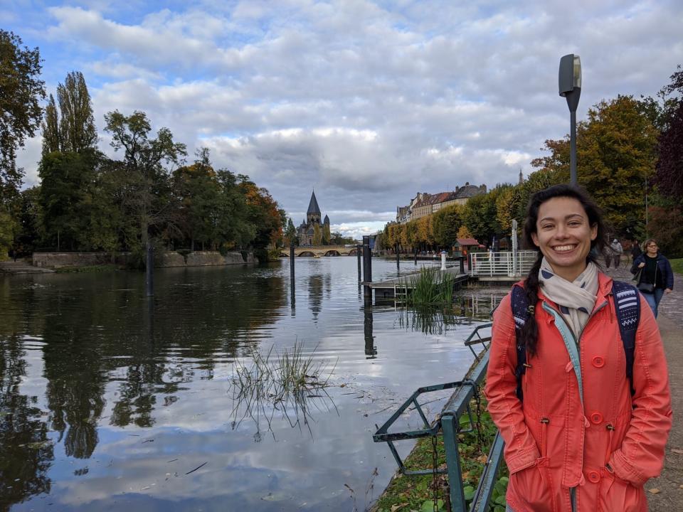 The writer smiles and poses in front of Metz, France